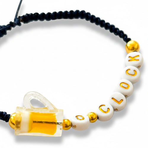 Beer Oclock bracelet with white beads, gold accents, and a beer  charm on a light background