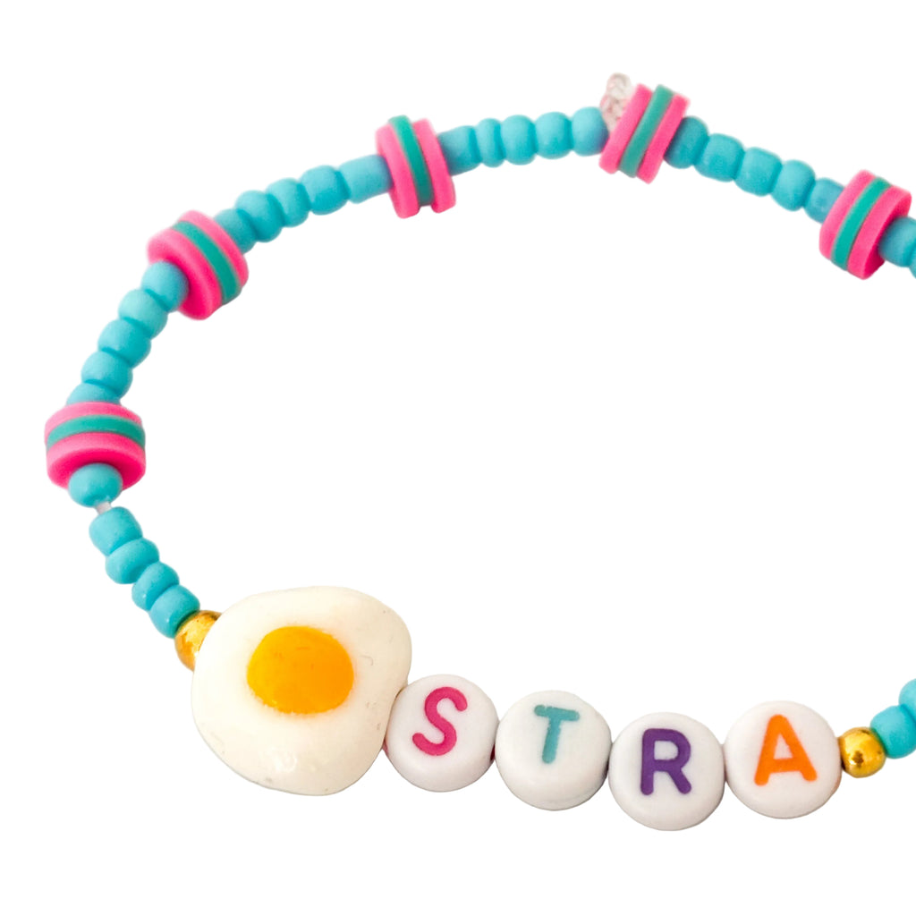 Colorful beaded bracelet with letter beads spelling 'EggSTRA' on a light background