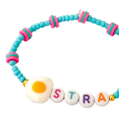 Colorful beaded bracelet with letter beads spelling 'EggSTRA' on a light background